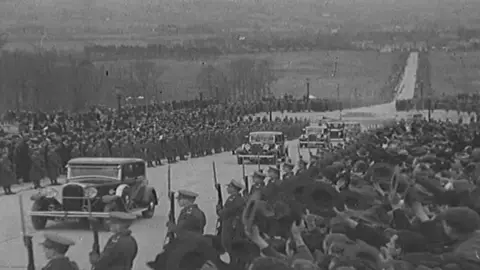 British Pathé Crowds of people watch as cars pass them on the road to Parliament Buildings at Stormont in the 1930s