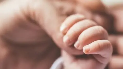 Getty Images Baby's hand and adult hand