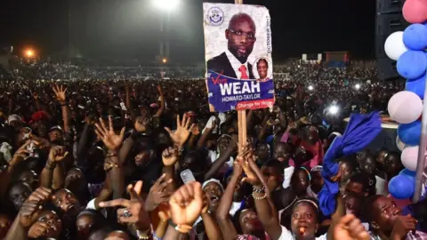 AFP Supporters of former international Liberian football star turned politician George Weah wave during a presidential campaign rally in Monrovia on October 6, 2017