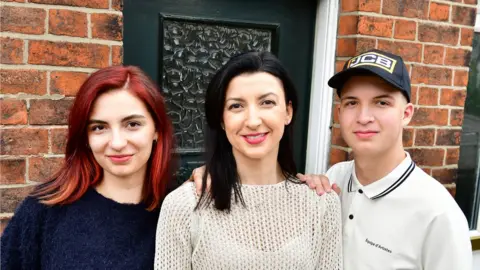 Nataliia Stepanenko with her children Diana and Denis outside their new home