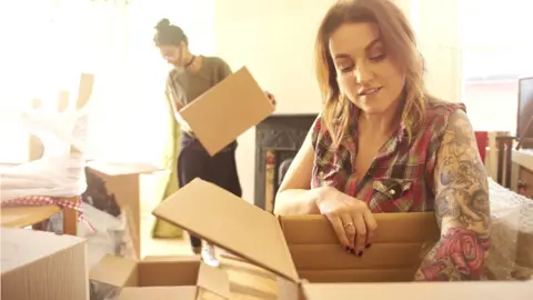 Getty Images Young woman packing a box as she moves house