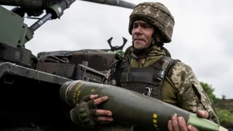 Reuters A Ukrainian service member carries an artillery shell. File photo