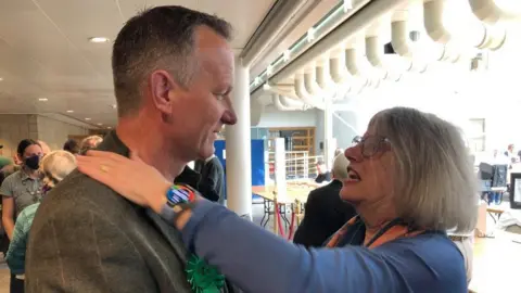 Vikki Irwin/BBC Suzie Morley being comforted by green leader Andy Mellen