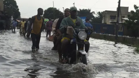AFP A taxi motocyclist rides on a flooded road at Okokomaiko in Ojo district of Lagos, on May 31, 2017.