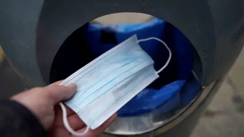 PA Media Face mask being thrown into a bin