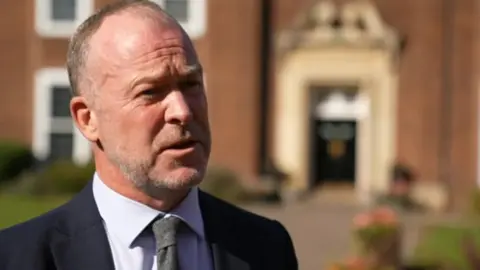 BBC A head teacher standing in front of a school building