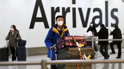 EPA People arriving from China in London on Wednesday. The UK - outside the EU - is asking for a pre-departure tests for Chinese arrivals from tomorrow