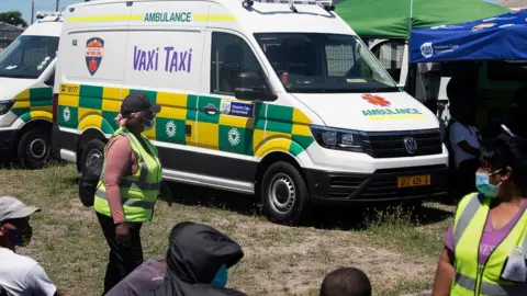 Getty Images A converted ambulance in South Africa, and people waiting to be vaccinated