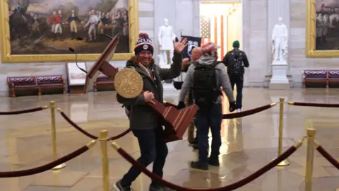 Getty Images One protester carries a plinth from a room in the US Capitol