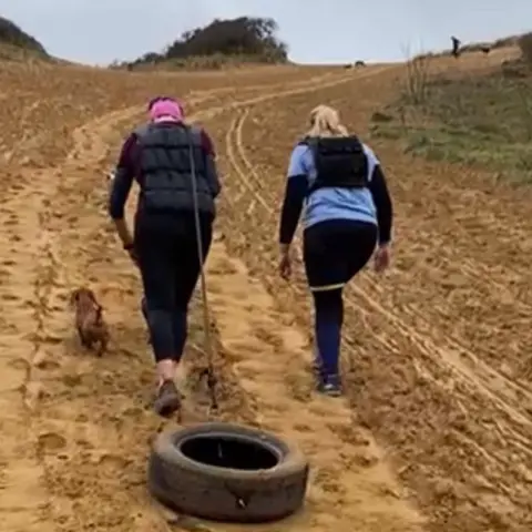 Antarctic Fire Angels Georgina Gilbert and Rebecca Openshaw-Rowe dragging a tyre up a sand duene