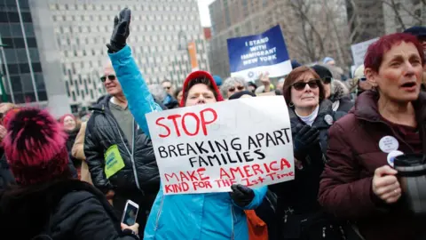 Getty Images A woman holds a sign saying "stop breaking apart families - make America kind for the first time"