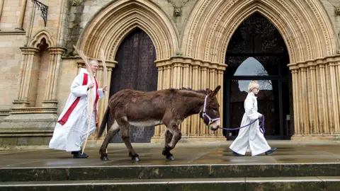 PA Media Canon Michael Gisbourne and a donkey called Lily.