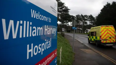 BEN STANSALL/AFP/GETTY IMAGES An ambulance driving by a sign for the William Harvey Hospital in Ashford, Kent