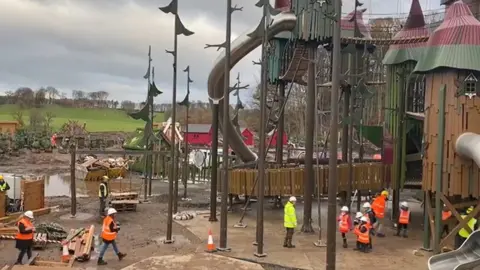 BBC Workers in hard hats with children visiting the site