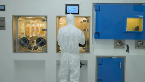 Siemens Healthineers A close up of a radiopharmacy. A worker dressed in lab clothing is carrying out some work. 