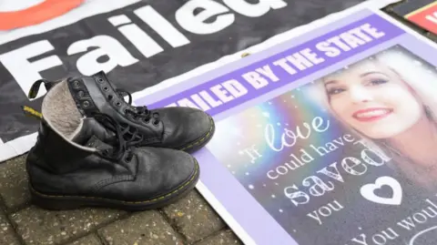 Boots of Tillie-Anne King next to her picture on the floor.