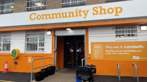 The front entrance to a community supermarket with mobility scooter parked outside