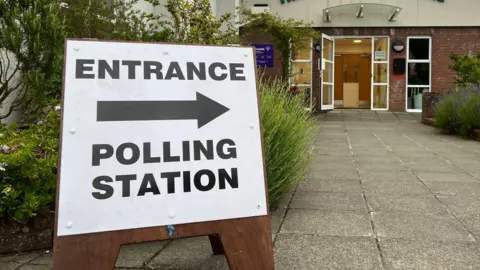 BBC A picture of a wooden sign which reads 'Entrance' with an arrow pointing to the right, with the words 'Polling Station' below.