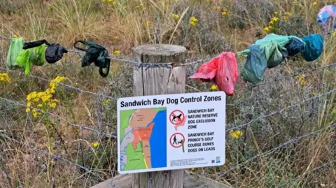 Kent Wildlife Trust Dog poo bags on fence at Pegwell