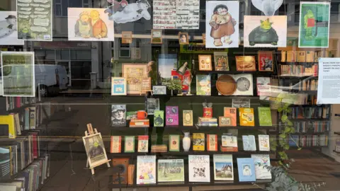 Oxfam A selection of books in a shop window with illustrations by Raymond Briggs above the bookcase