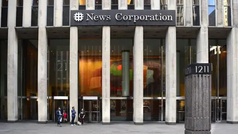 Exterior image of an office building with the words "News Corportation" on it, some people are in the foreground of the image walking.