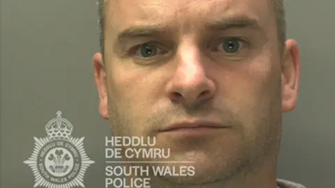 Foto Christopher Cooper dari Polisi Wales Selatan. Dia memiliki rambut pendek berwarna abu-abu. 