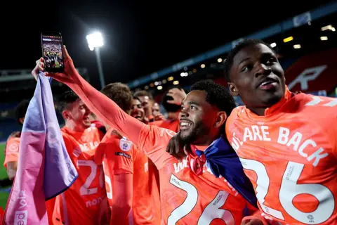 Getty Images Jay Dasilva of Coventry City holds his phone aloft, filming as players celebrate around him