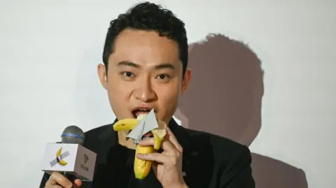 Getty Images Chinese crypto entrepreneur Justin Sun pictured eating a banana which was part of an artwork he paid $6.2m for