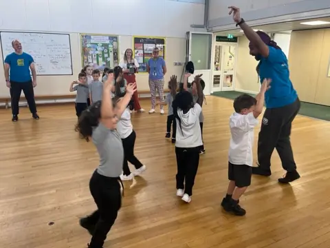 A group of six children dancing along with a teacher