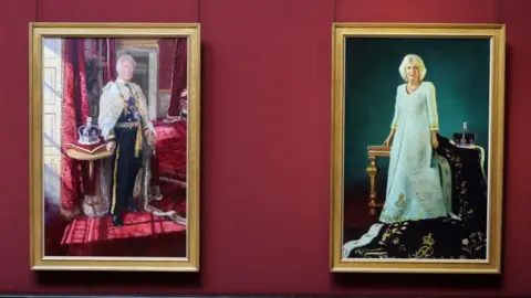 The two portraits side by side hanging in the gallery