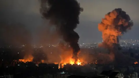 EPA Smoke rises as a result of an Israeli airstrike at Dahieh Saint Therese area in the southern suburb of Beirut. An orange flash of fire can also be seen in the foreground