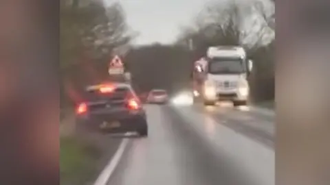 A grey BMW swerving from the road onto the grass verge
