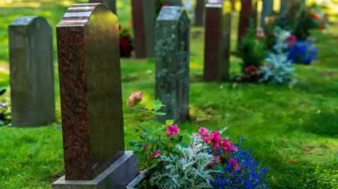 Getty Images Graveyard with pink and blue flowers by it.