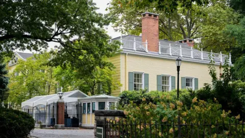 Bloomberg via Getty Images The exterior of Gracie Mansion in New York City. It has yellow clapboard sides, green shutters, and white railings along the roof.
