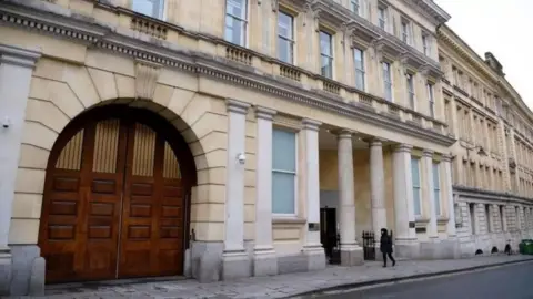 Getty Images The exterior entrance of Bristol Crown Court. It is a large sand coloured building with large white columns outside the front, and large arched wooden double doors on the left.