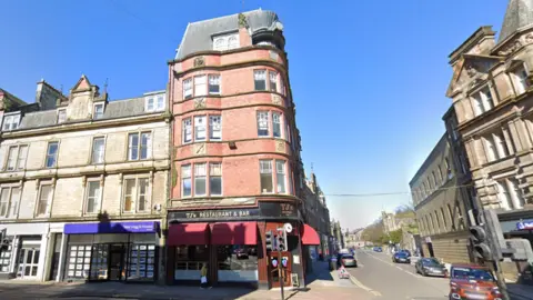 Google A four-storey red brick office building on the corner of a street with a pub underneath