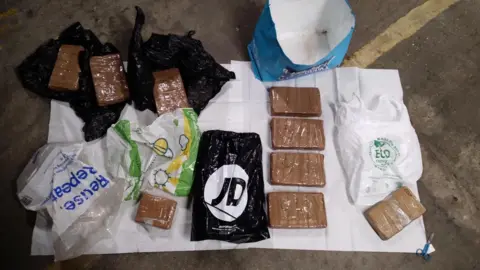 Essex Police Nine brown bricks of cocaine laid out on a white sheet. There are also various carrier bags.