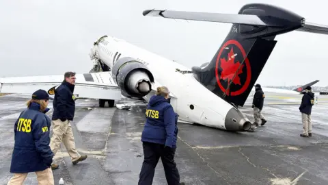 National Transportation Safety Board (NTSB) investigators inspect the wreckage of an Air Canada Express jet that collided with a fire truck at LaGuardia Airport in Queens, New York, U.S., March 23, 2026.