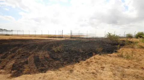 SIMON COLLYER Middlewick Ranges can be seen badly burned, with a lot of the ground black from the fire.
There is a fence in the background.