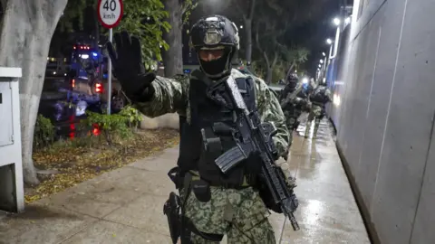 A heavily armed Mexican police officer stands guard outside a police station in Mexico City.