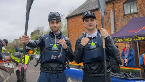 Ben Watkins and Oliver Smee both in kayak gear, holding oars and smiling.