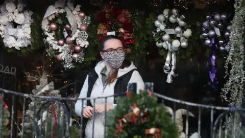 PA Media A person wearing a face covering walks passed Christmas wreaths for sale at All Occasions Designer florist in Denny.