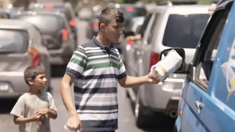 Muhammad sells tissues to passing cars in Lebanon