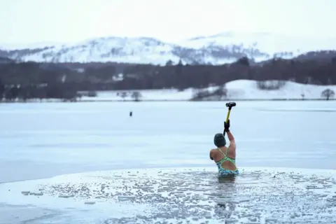 Reuters Alice Goodridge breaks the ice at Loch Insh, Scotland, 30 December 2020.