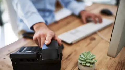 Getty Images Man holding the receiver of a telephone at work
