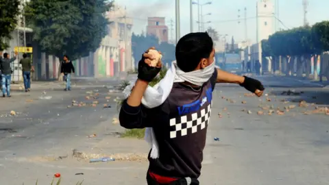 Getty Images A young man throwing a stone in a street filled with smoke