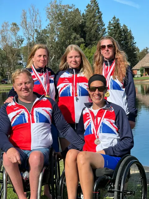 John Liscomb Williams stands behind two team mates in a wheelchair at World Championship Water Skiing event in California.