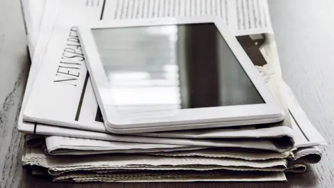 Getty Images Newspapers and an tablet