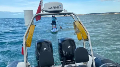 Will Chetwode Joe Cartwright on a paddleboard by his support boat on the English Channel