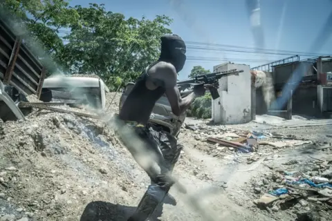 Getty Images Een gewapend lid van de G-9-bende bij een zwaar versterkte wegversperring in het centrum van Delmas 6 op 9 mei in Port-au-Prince.